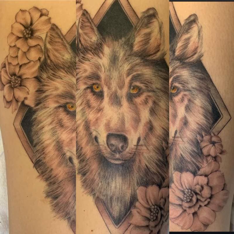 Black and grey realistic wolf with flowers on upper arm