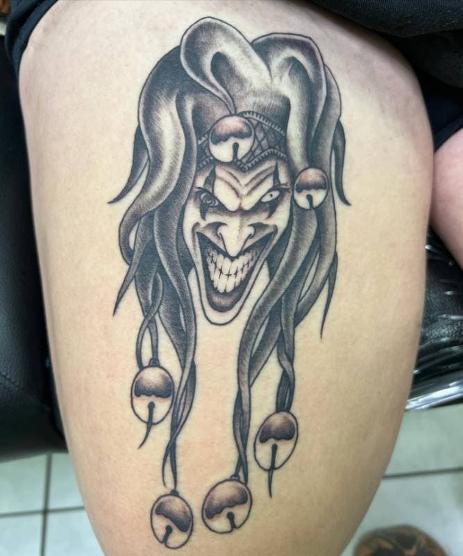 Black and grey sinister jester tattoo on thigh